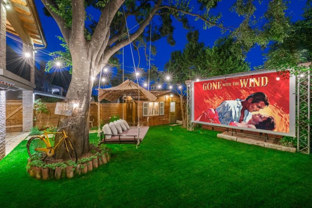 Vanjsko kino u vrtu s osvijetljenim panoom i lampicama noću
